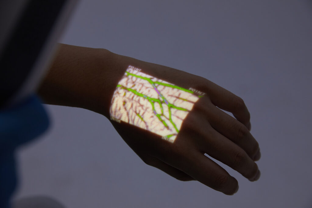 hellovein projecting green vein pattern on hand in dim light