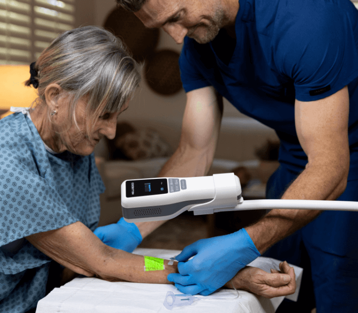 Medical professional using the Hellovein Lite 2.0 device with trolley for vein access on an elderly patient.