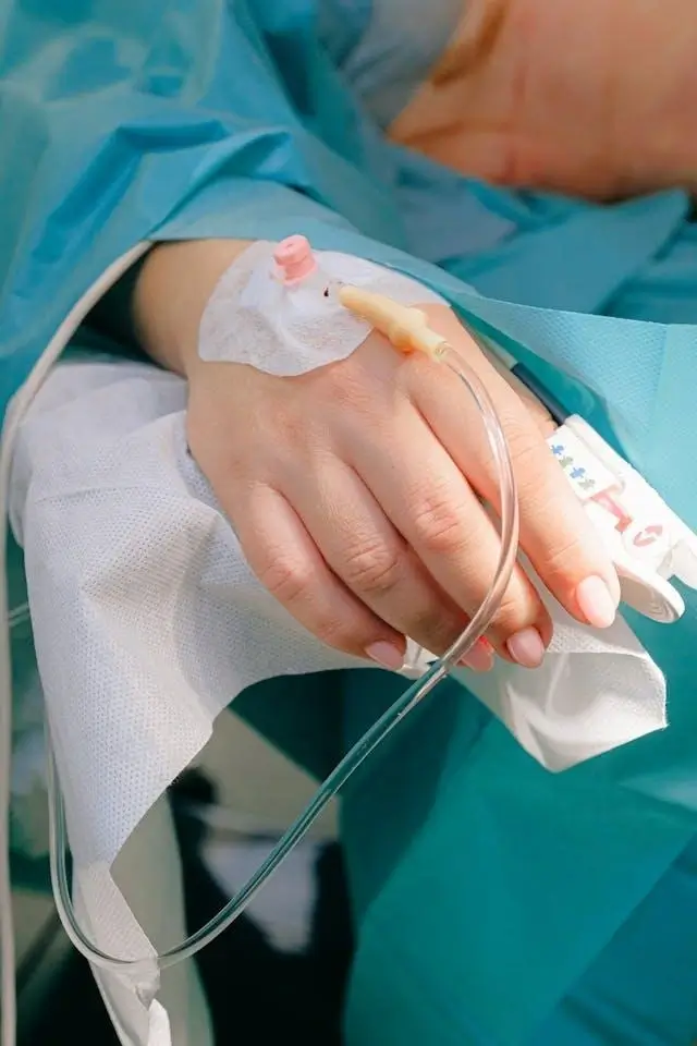 Patient’s hand with an intravenous catheter for IV infusion therapy, monitored by medical staff during hospital treatment