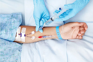 Der Arzt verabreicht das Medikament durch eine intravenöse Injektion in den Arm des Patienten.