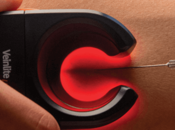 Un clínico realiza una venopunción con Veinlite iluminando las venas.